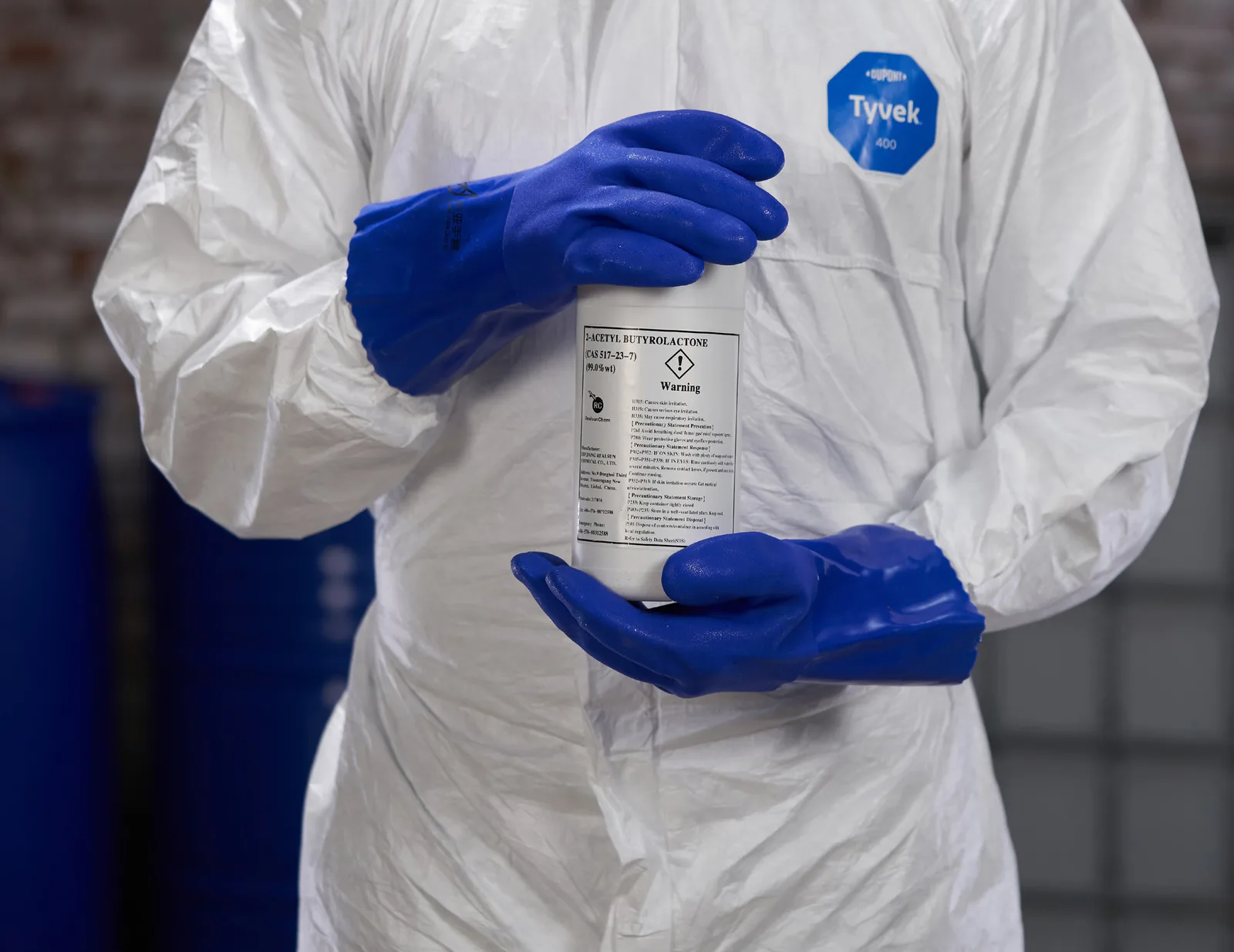 Blue 806-series PVC gloves used while handling an industrial chemical container