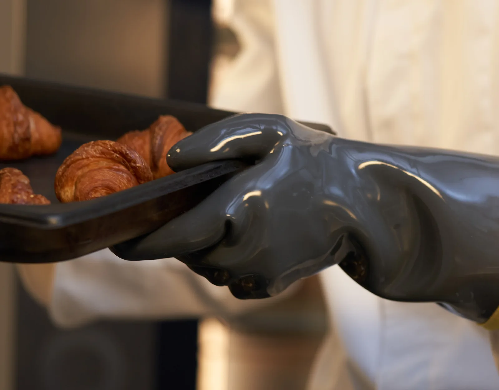 Dark gray 908 heat-resistant PVC gloves holding ovenware in a bakery setting