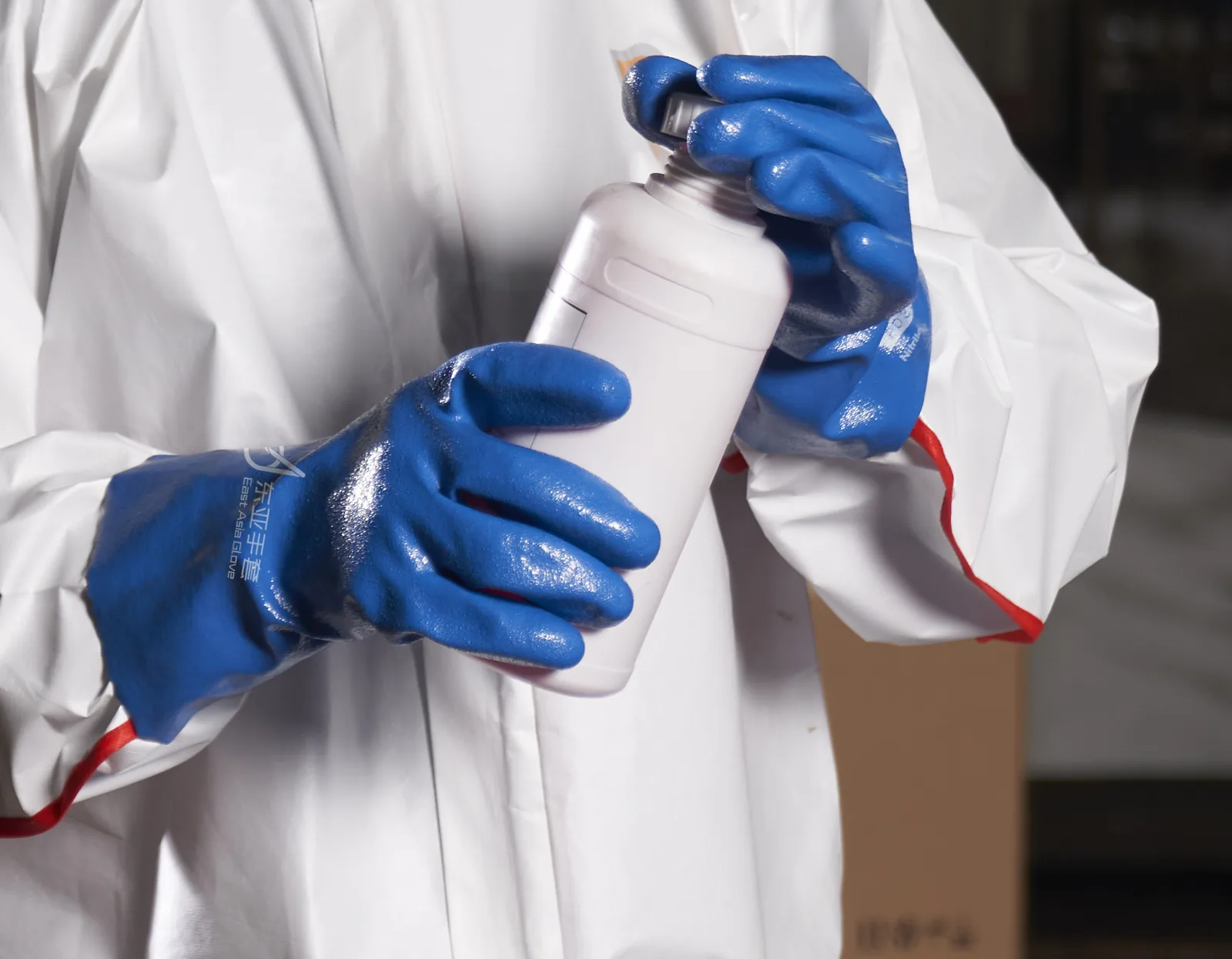 Blue 338-series nitrile gloves holding an industrial chemical bottle