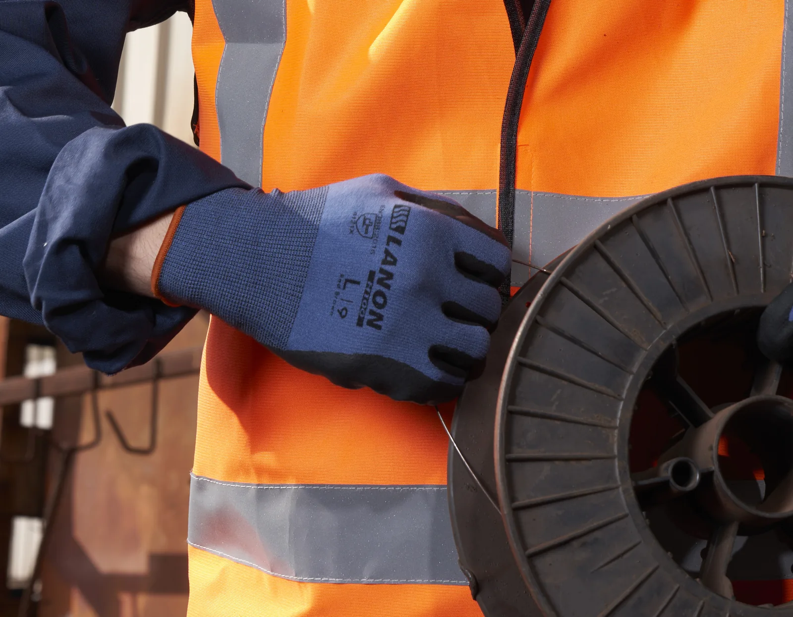 Black H-series mechanical gloves handling a cable spool