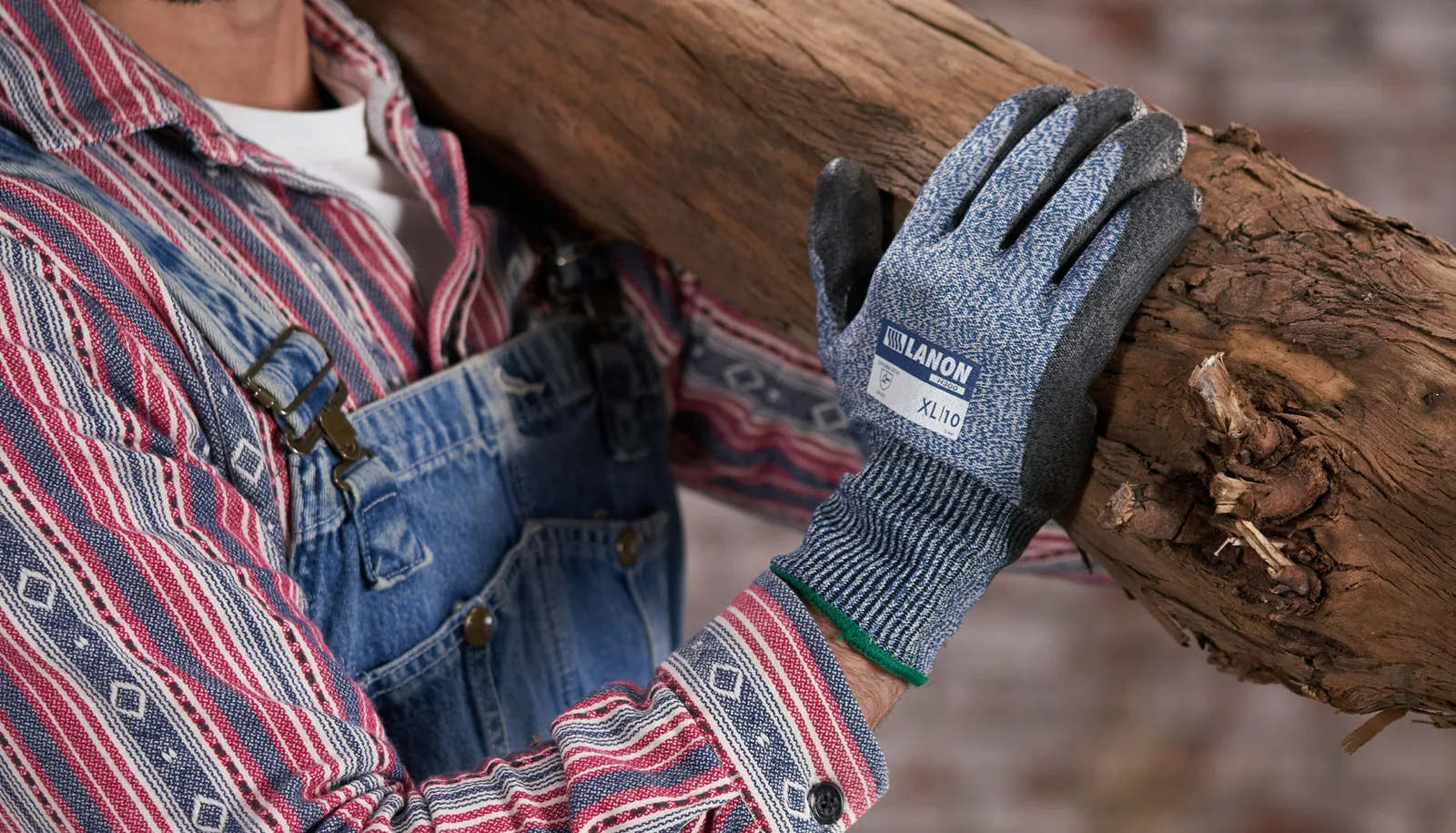 Gray H300 mechanical gloves carrying a rough timber log